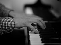 a black and white photo of a person playing a piano